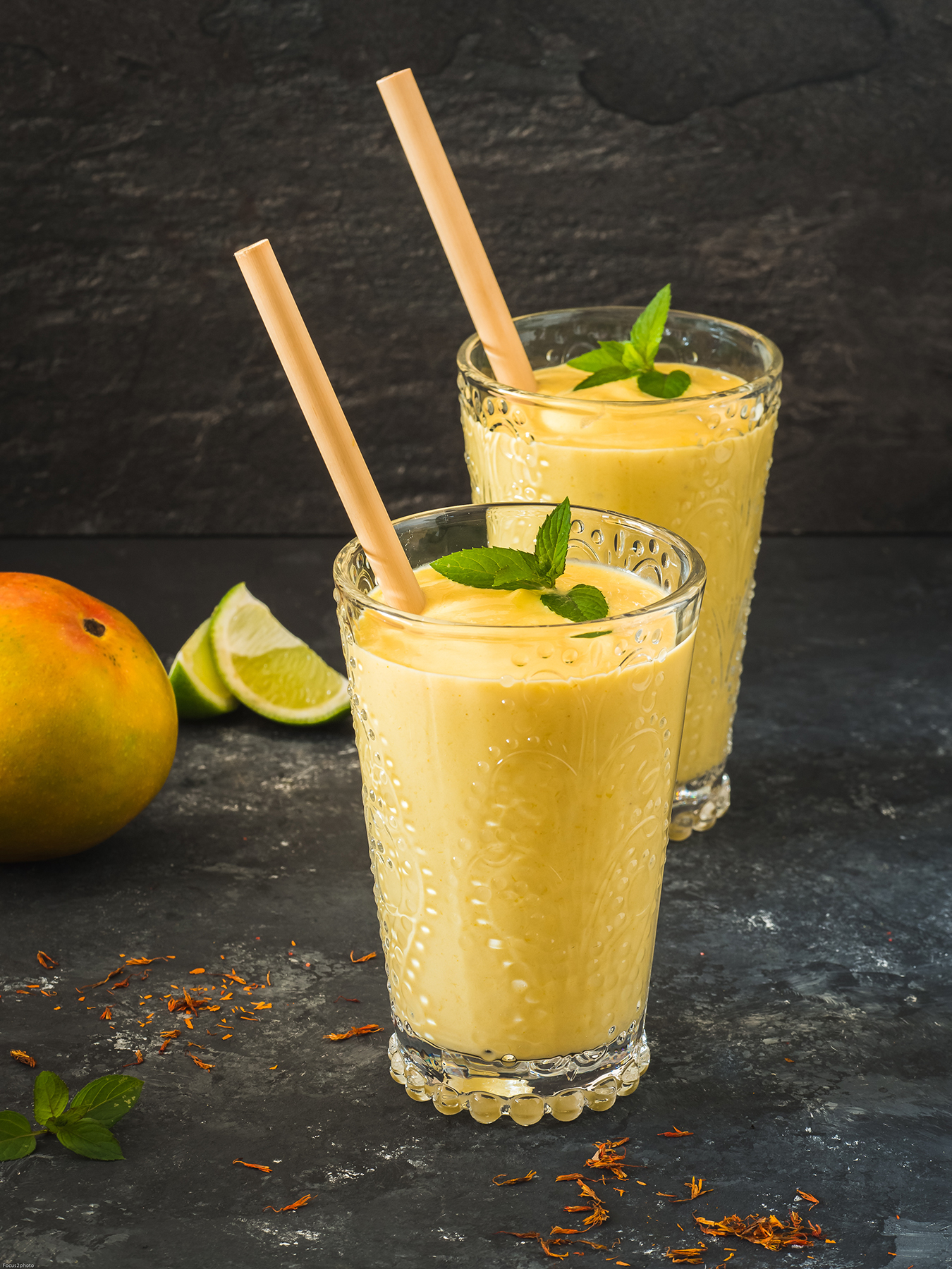 Two glasses of mango lassi with straws